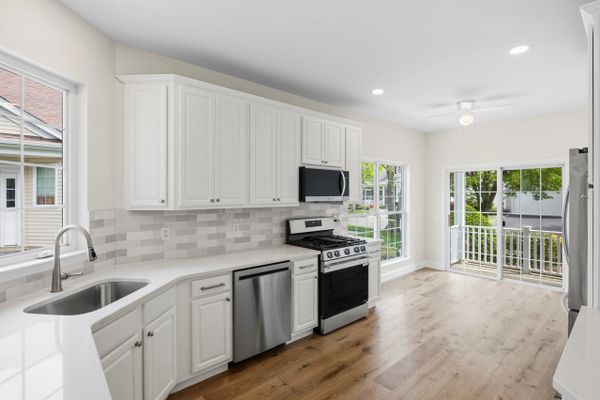 Bright modern kitchen with white cabinets and stainless steel appliances.