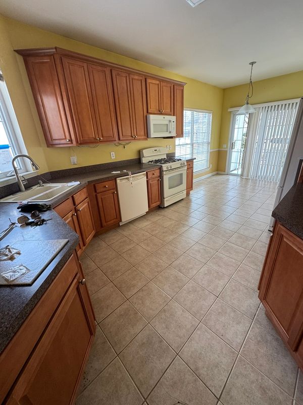 Bright kitchen with wooden cabinets and tiled floor.