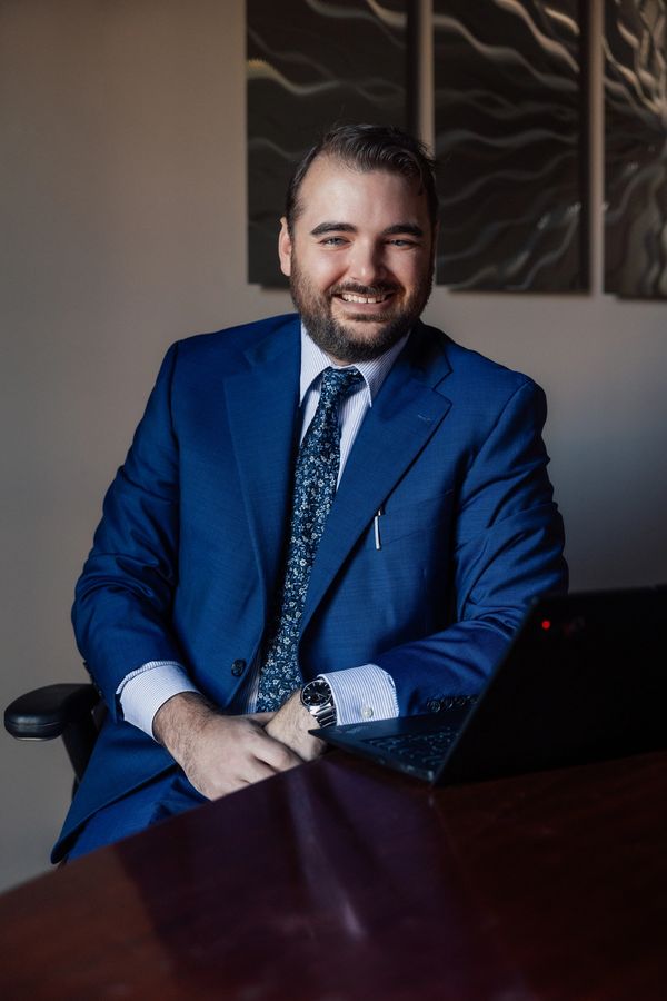 a white male in a blue suit with a big smile wearing a silver watch