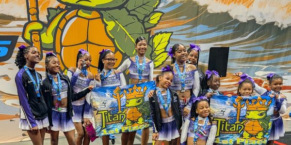 Group of girls in cheer uniforms holding first place banners.