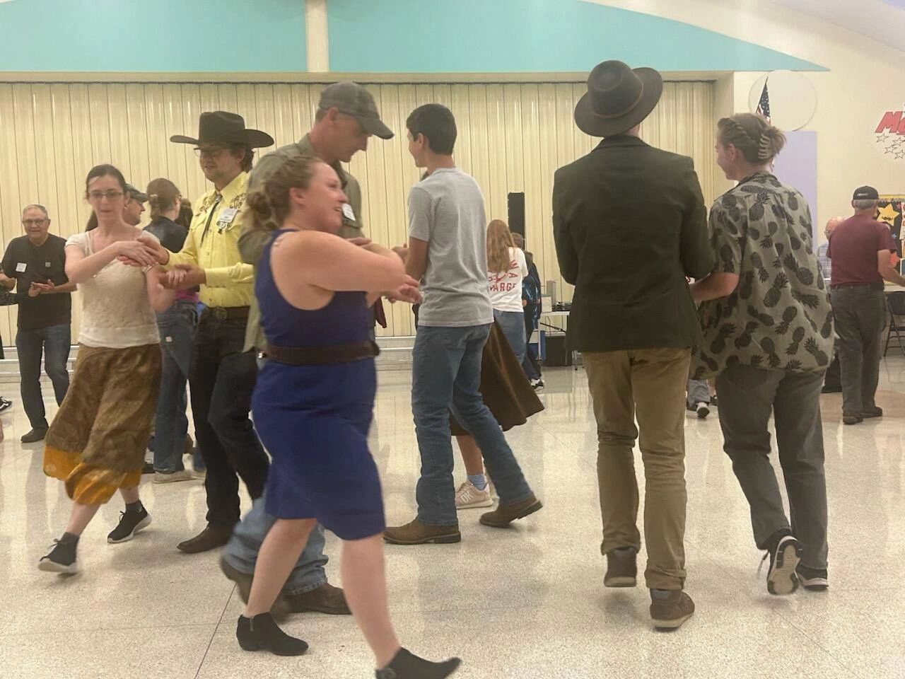 People dancing in a casual indoor setting, some wearing hats and costumes.