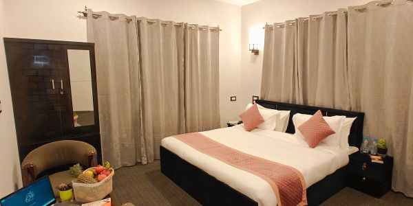 Cozy hotel room with a double bed and beige curtains.