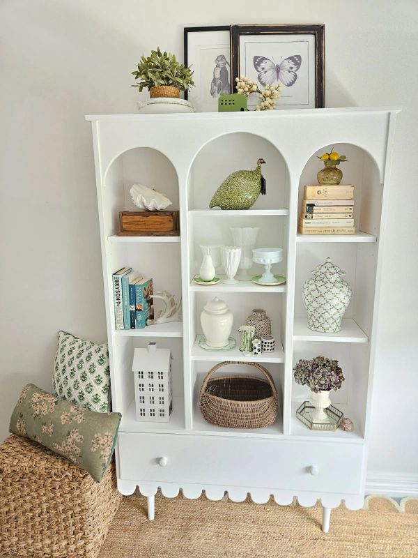 White display cabinet with decorative items and wicker basket.