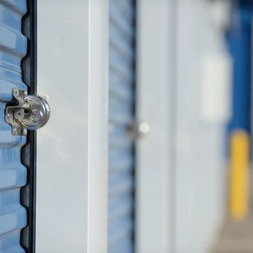 Close-up of secure, locked white metal doors at a clean storage unit facility.