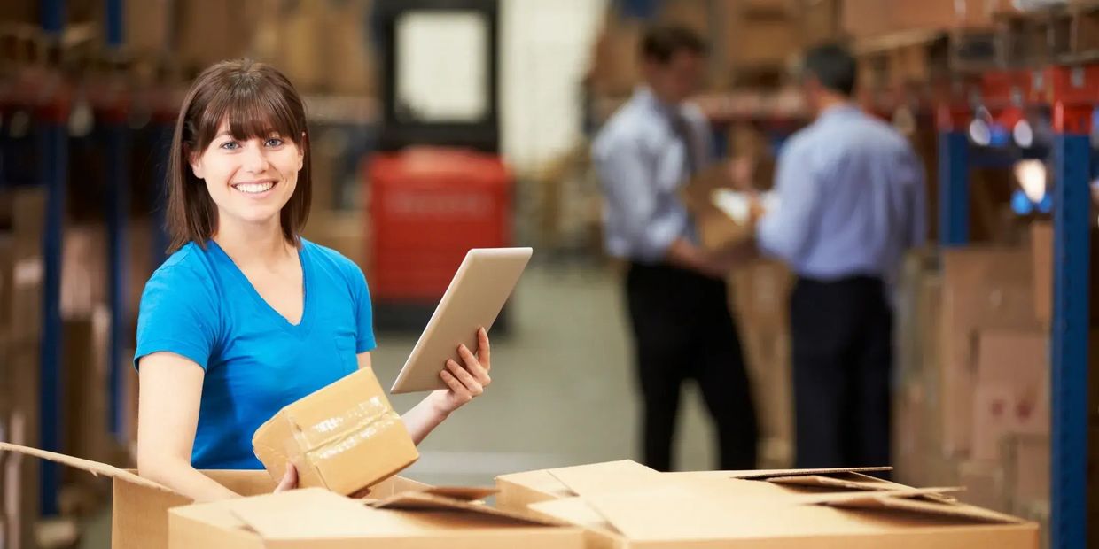 Warehouse manager holding a tablet and package, overseeing commercial moving and storage operations.