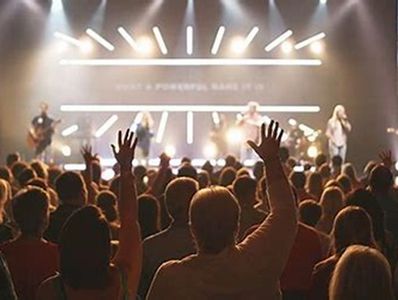 Audience raising hands during a live concert with stage lighting.