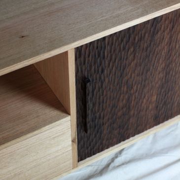 Wooden cabinet with textured dark door and light open shelf.