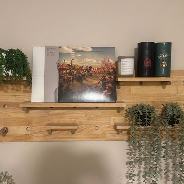 Wooden wall shelf with plants, vinyl records, and decorative containers.