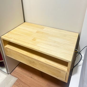 A modern floating wooden drawer with clean lines against a white wall.