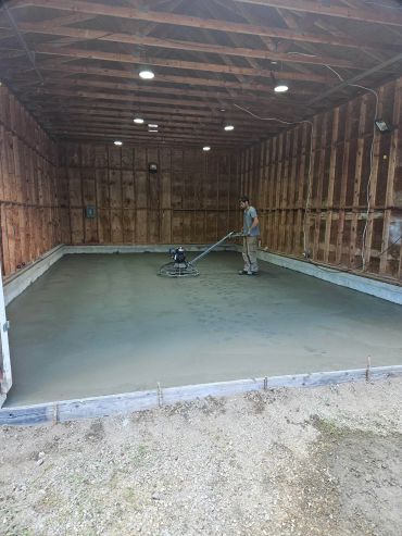 Worker smoothing concrete inside a wooden structure.
