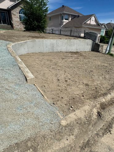 Empty yard with concrete retaining wall and gravel path.