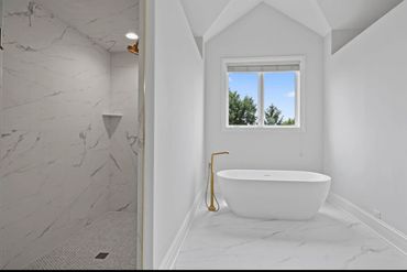 Modern bathroom with a freestanding bathtub and marble shower.