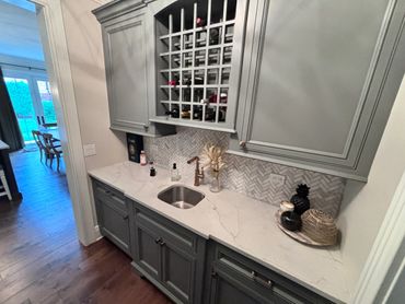 Stylish kitchen nook with gray cabinetry, wine rack, and marble countertop.