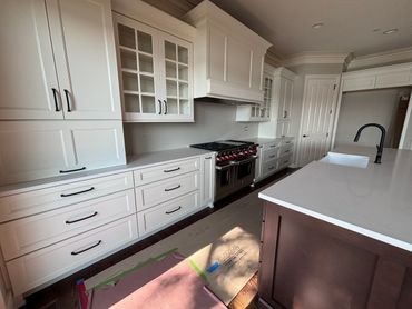 Modern kitchen with white cabinets, stainless steel stove, and dark island.