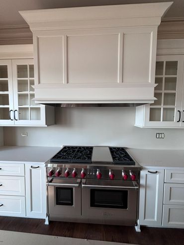 Modern kitchen with stainless steel stove and white cabinetry.
