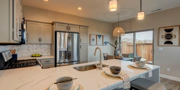 Modern kitchen with marble island and pendant lights.