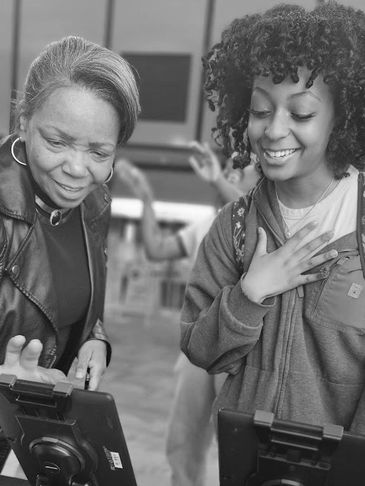 Two women happily interacting with tablets in a public indoor space.