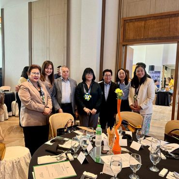 Group of seven people posing by a dining table at an indoor event.
