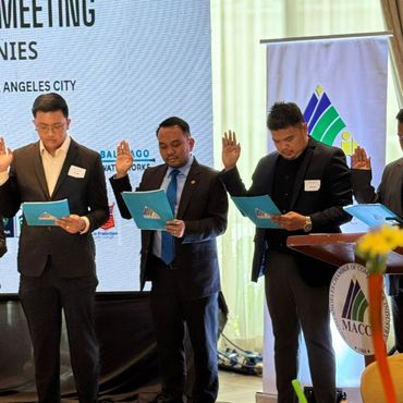 Men in suits taking an oath at a formal event with documents in hand.
