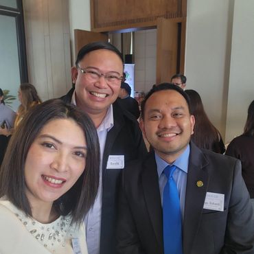 Three professionals smiling together at a formal event.