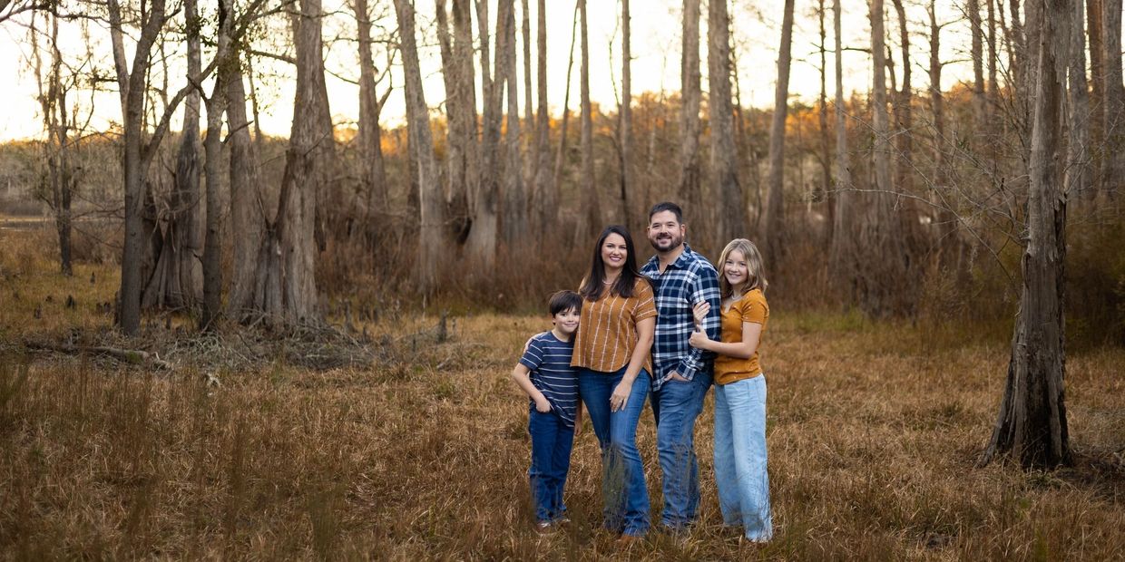 Family of four standing in cypress forest.