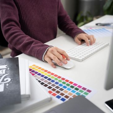 a sign designer working at her computer with a color palette on the desk