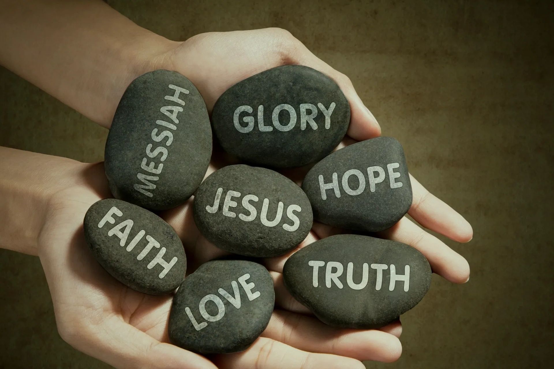 Hands holding stones with words of encouragement. Glory, Jesus, Hope, Love, Truth, Messiah, Faith