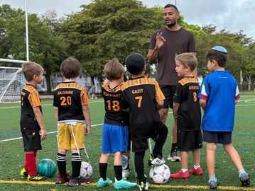 Kids soccer team listening to coach on the field.