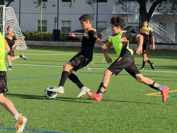Two kids fiercely competing for a soccer ball on a field.