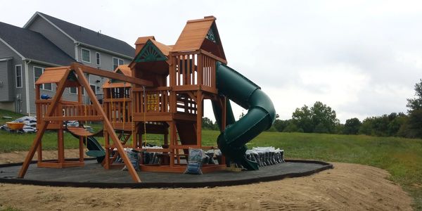 A picture of the swing set and the green slider outside the house
