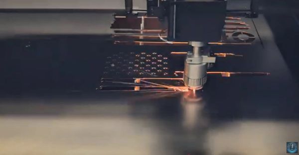 Laser cutting an American flag design on a metal sheet.
