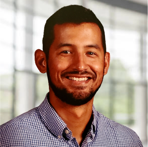 Portrait of a smiling man in a checkered shirt with a blurred background.