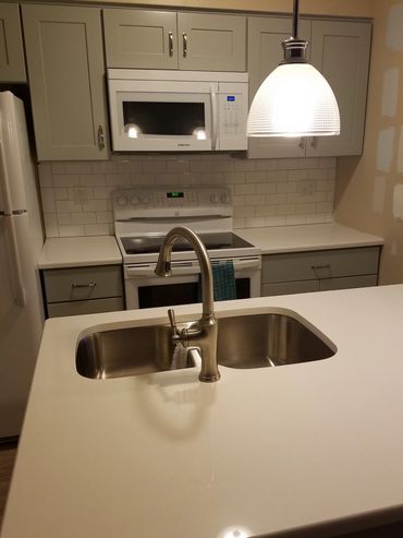 A kitchen island with a sink and hanging light