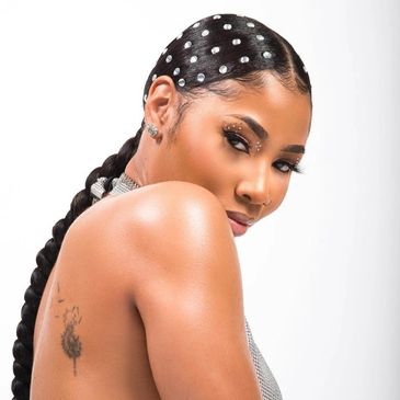 Woman with pearl-adorned braided hair and a tattoo on her shoulder.