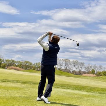 Golfer swinging club on a golf course.