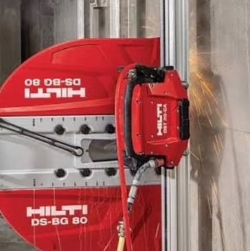 Worker operating a Hilti DS-BG 80 wall saw on a construction site.