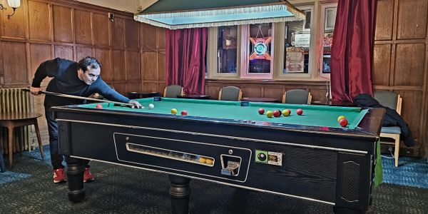 Man playing billiards in a cozy pub with wooden paneling and vintage decor.