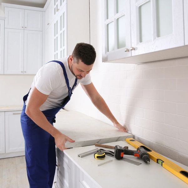 Worker installing new countertop in modern kitchen