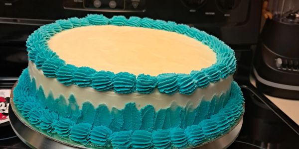 Round cake with blue and white icing decorations.