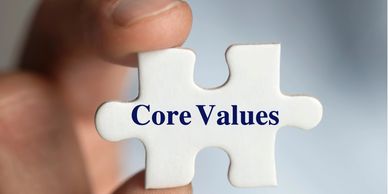 White puzzle piece held between finger and thumb. Puzzles piece is titled 'core values'