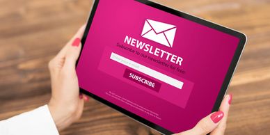 Woman holding iPad with the words 'newsletter' on the screen