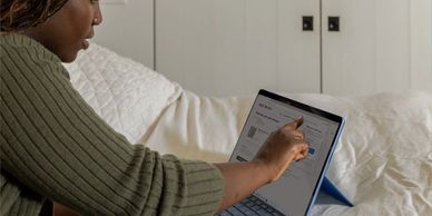 A woman sitting on a bed working on a laptop
