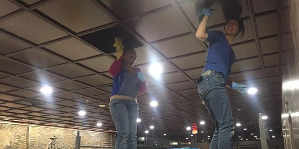 people cleaning a tile ceiling
