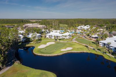 A serene golf course with water hazards and nearby residential buildings.