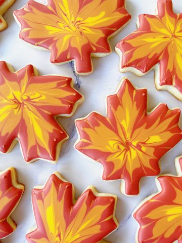 Maple leaf-shaped autumn cookies with red and yellow icing.