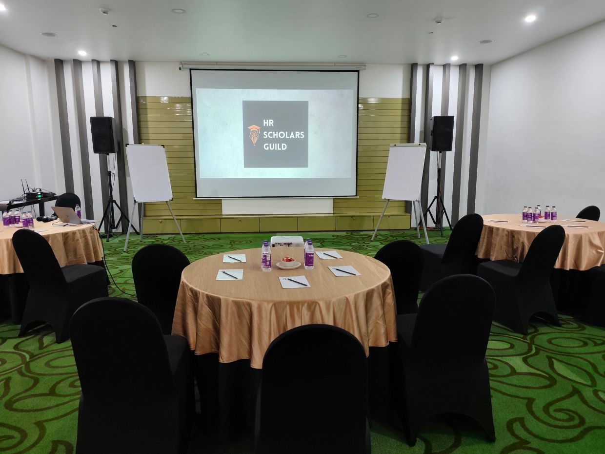 Conference room setup with tables, chairs, and presentation screen.