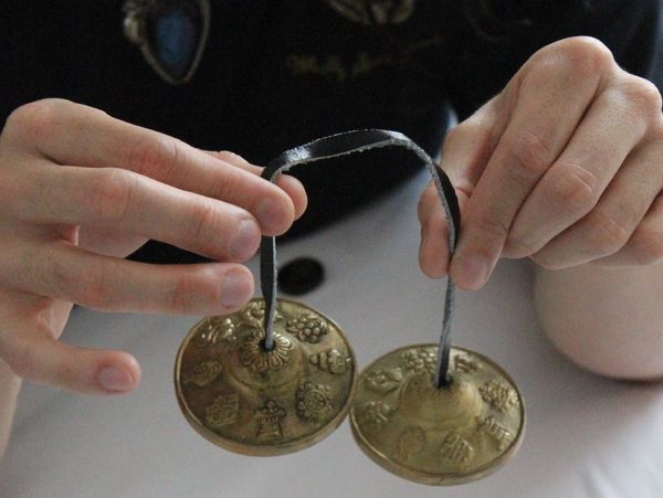 Therapist holding Reiki bells symbolizing energy balance at Wholly Spirit Hands Sugar Land.