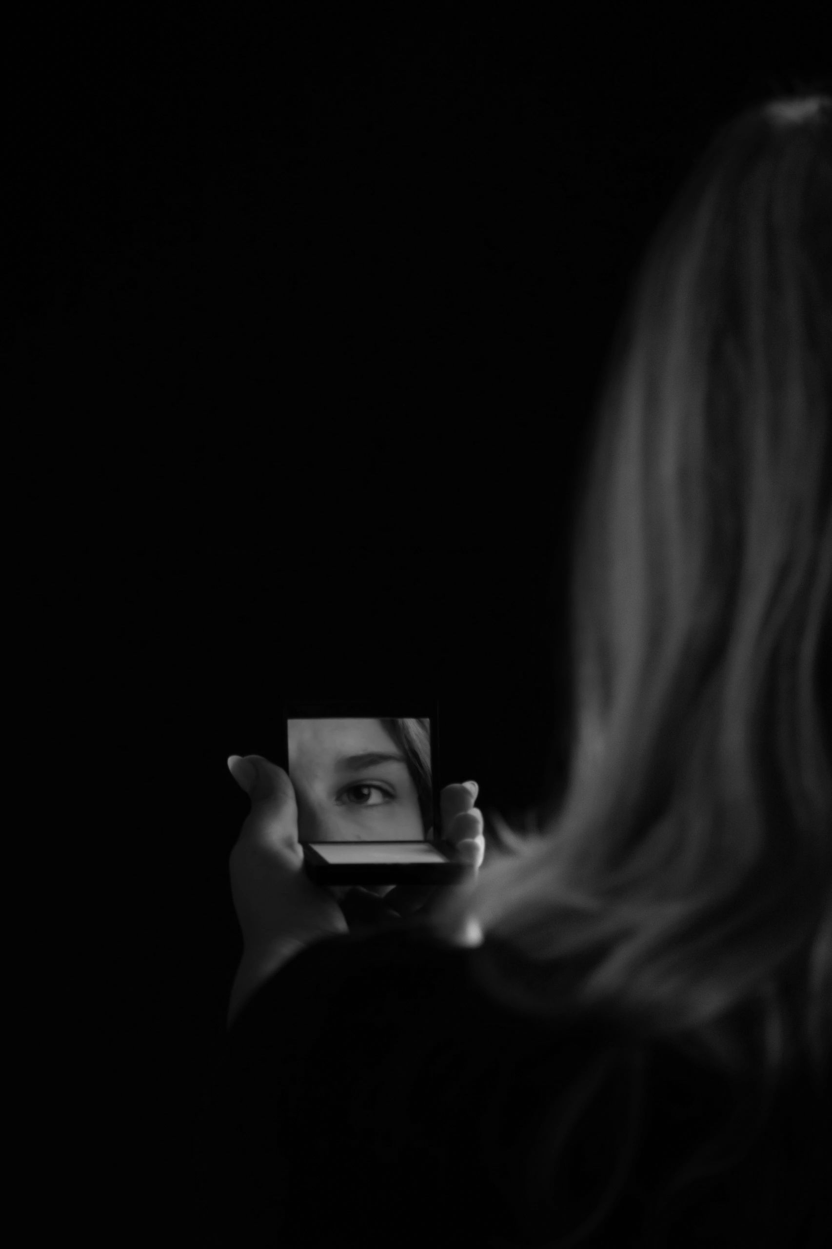 Creative portrait of a woman's eye reflected in a handheld mirror, photographed by Bona Photography.