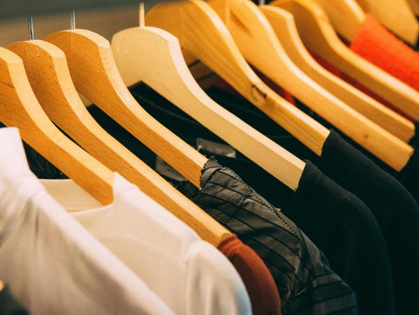 Clothes hanging neatly on wooden hangers in a wardrobe.