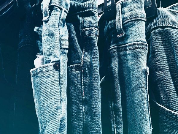 Close-up of blue jeans hanging side by side.